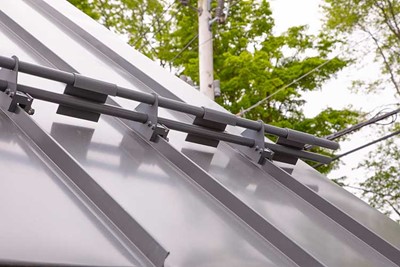 Fence-style snow guard with two bars installed on a metal roof. 