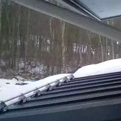 AceClamp metal roof snow guards securing heavy snow loads on a residential roof.