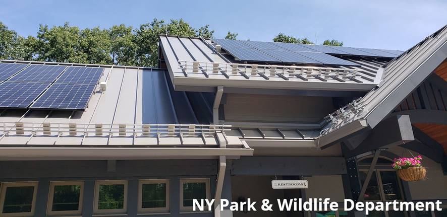 NY Parks and Wildlife project shows snow guards below solar panel installation on standing seam metal roof.