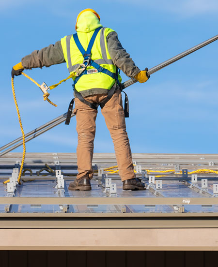 Contractor installing ColorSnap snow retention solution in front of solar panels at CT DEP building.